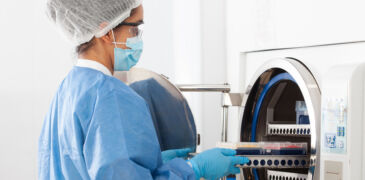 young female scientist sterilizing laboratory material in autoclave