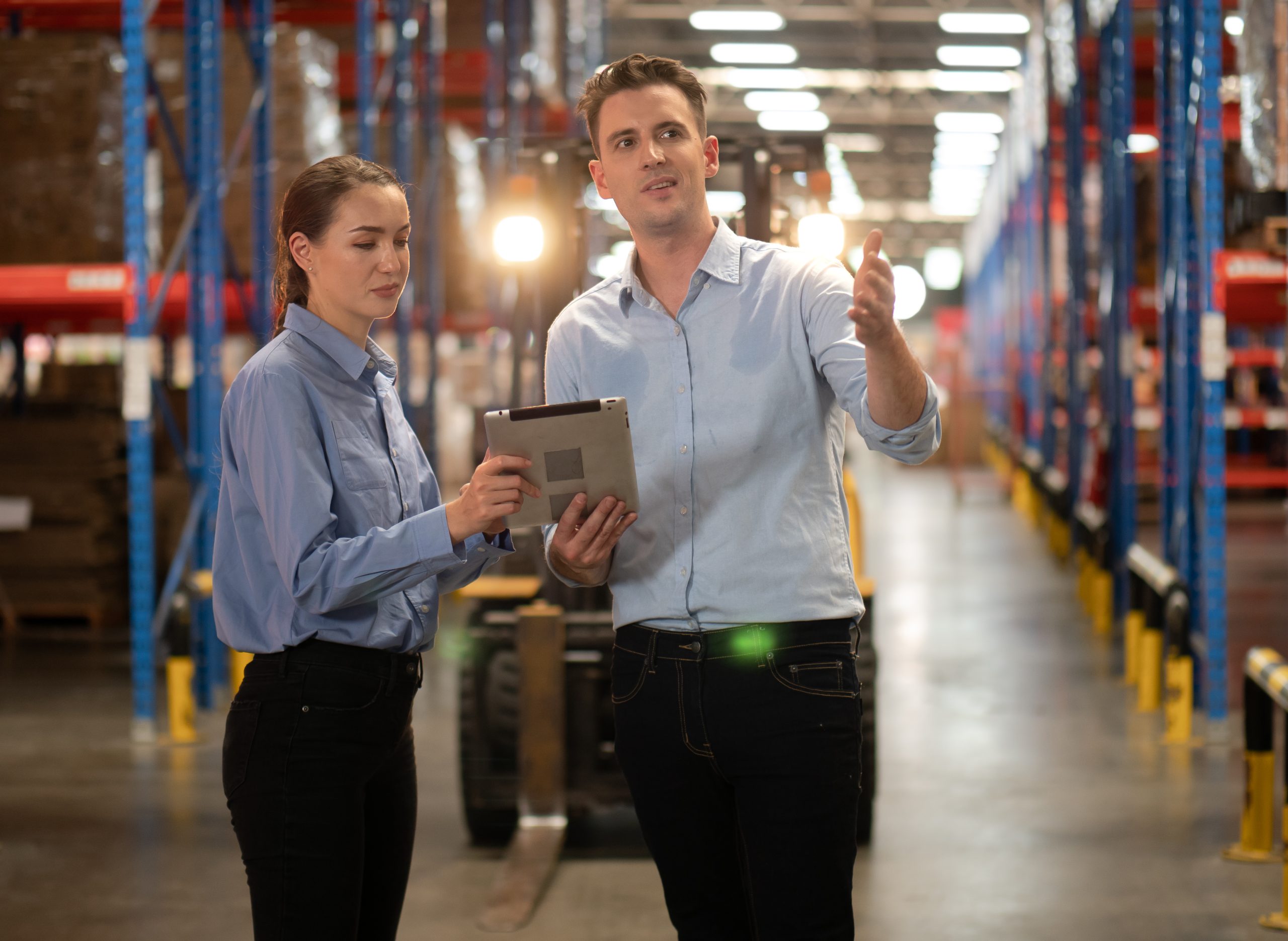distribution warehouse manager and client businesswoman using digital tablet checking inventory storage on shelf.